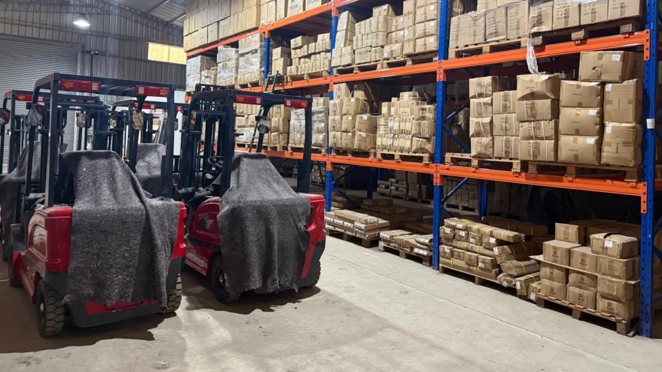 Interior del depósito con autoelevadores y racks cargados de cajas PROIN