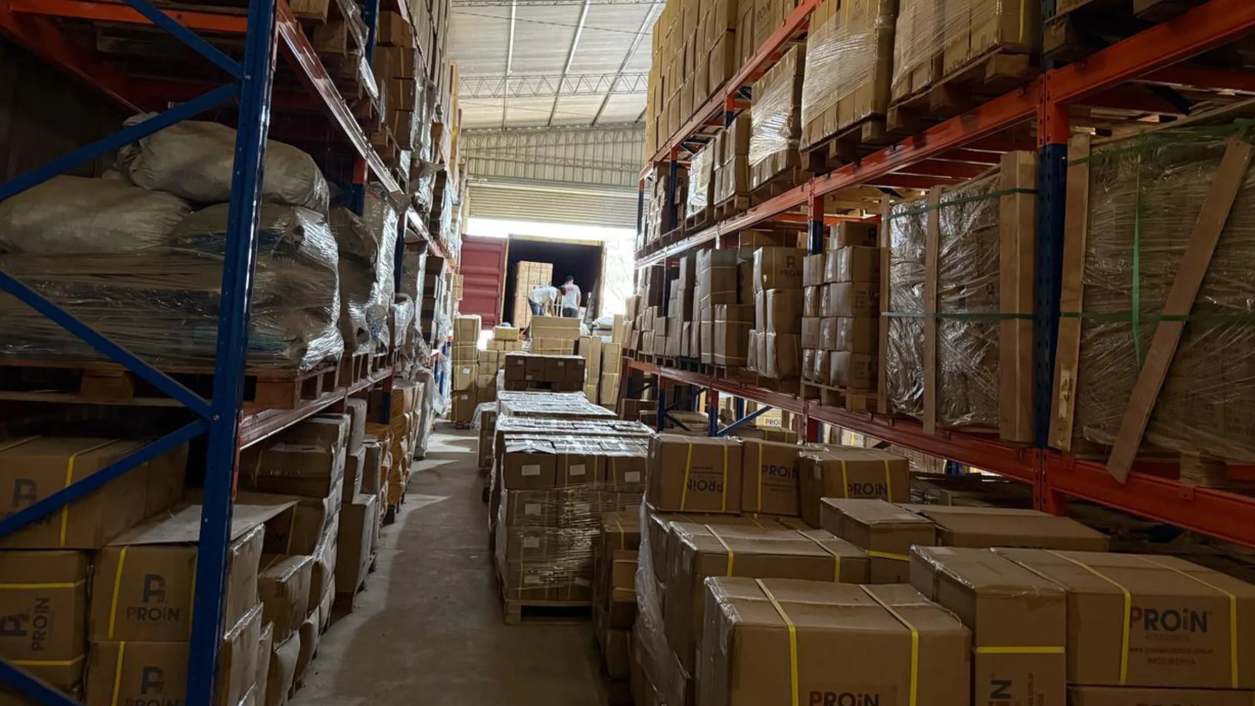 Pasillo del depósito con racks llenos de cajas de accesorios PROIN